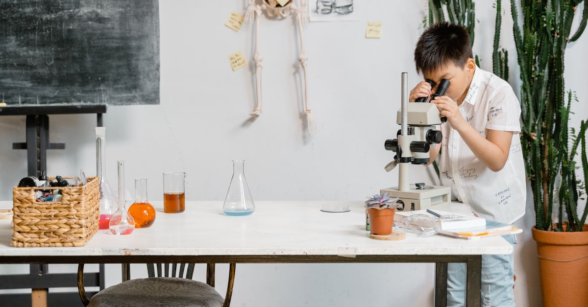 A young boy in a laboratory examining samples through a microscope for educational purposes.